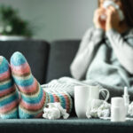 Sick woman with flu, cold, fever and cough sitting on couch